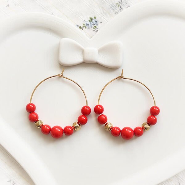 boucles créoles dorées avec perles rouges et dorées, style élégant et coloré.