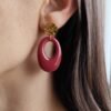 Boucle d'oreille pendante avec pendentif ovale bordeaux en résine et clou d'oreille en acier inoxydable martelé doré.