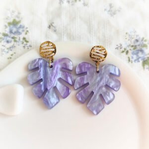 Boucles d'oreilles violettes en forme de feuille monstera avec paillettes et attache dorée martelée.