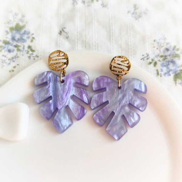 Boucles d'oreilles violettes en forme de feuille monstera avec paillettes et attache dorée martelée.