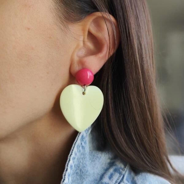 Boucle d'oreille pendante avec pendentif en forme de cœur jaune pâle en résine et clou d'oreille rose en résine.