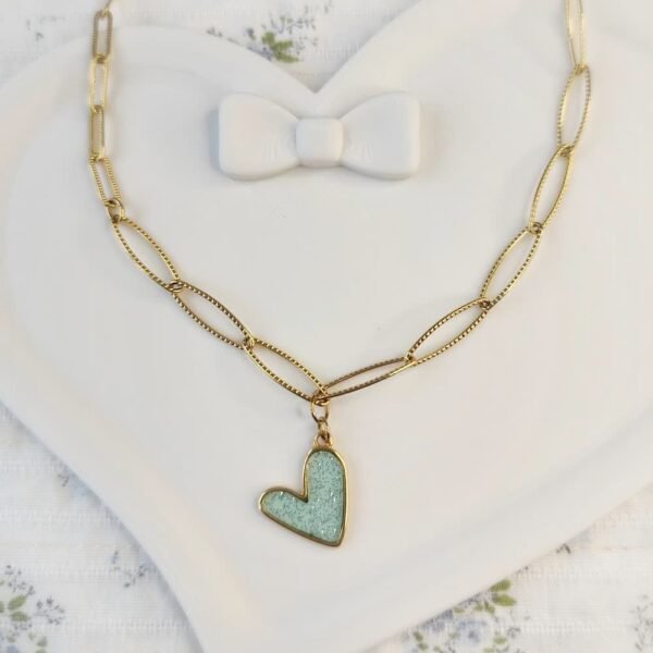 Collier doré avec pendentif cœur bleu pailleté posé à plat