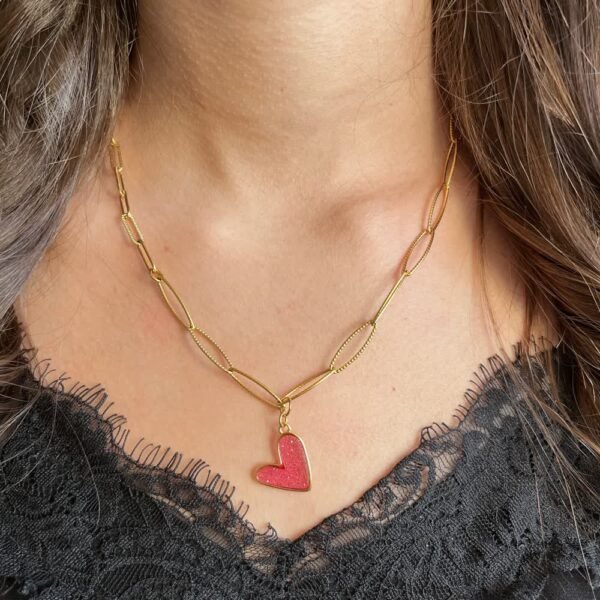 Collier doré avec pendentif cœur rose porté autour du cou