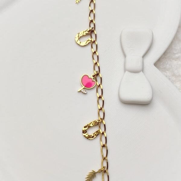 details-bracelet-breloques-tulipe Détails d'un bracelet à chaîne dorée avec breloques dorées et roses.